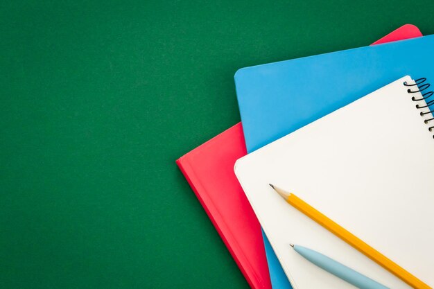 Notebooks on green background school concept flat lay