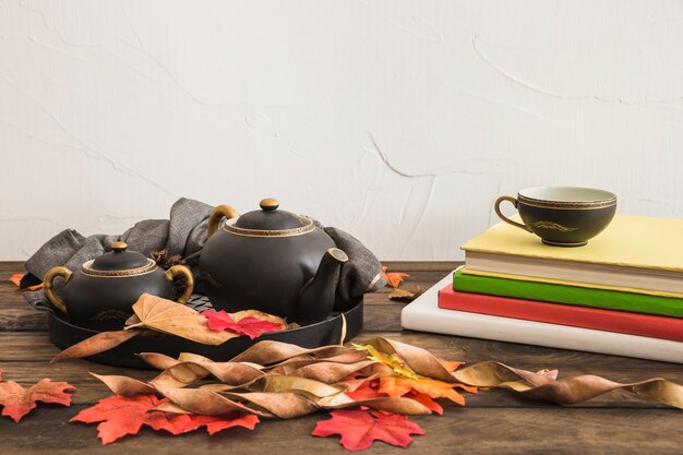 Notebooks and leaves near tea set