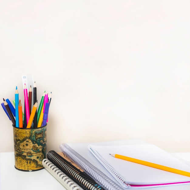 Notebooks near cup with pencils