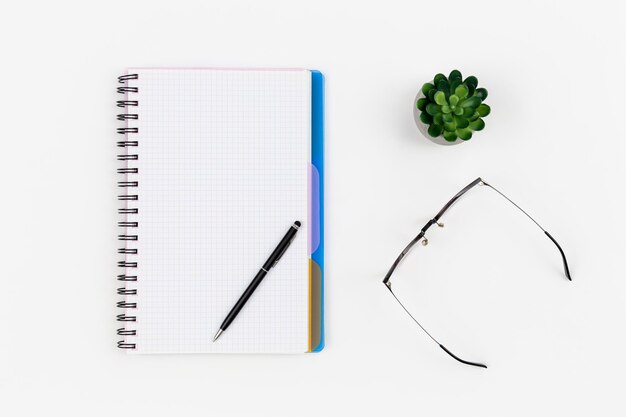 Notepad glasses and pen on a white background top view