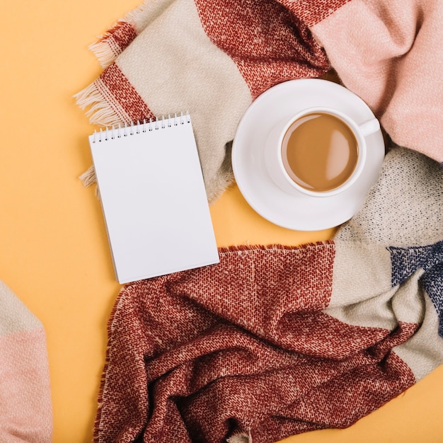 Notepad near cup and scarf