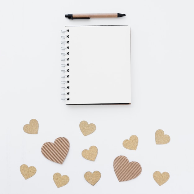 Notepad near pen and ornament hearts 