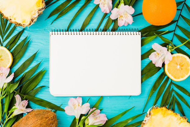 Notepad among plant leaves and fruits near flowers