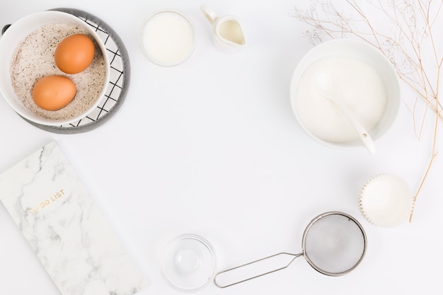 Notepad; tasty ingredient and baking ingredient arranged in circular pattern on background