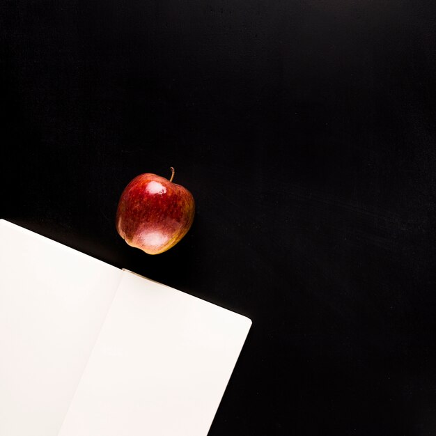 Notepad with fruit on black desk