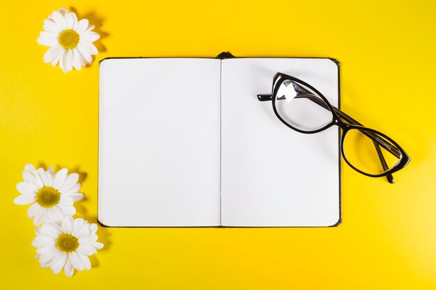 Notepad with glasses and white flowers