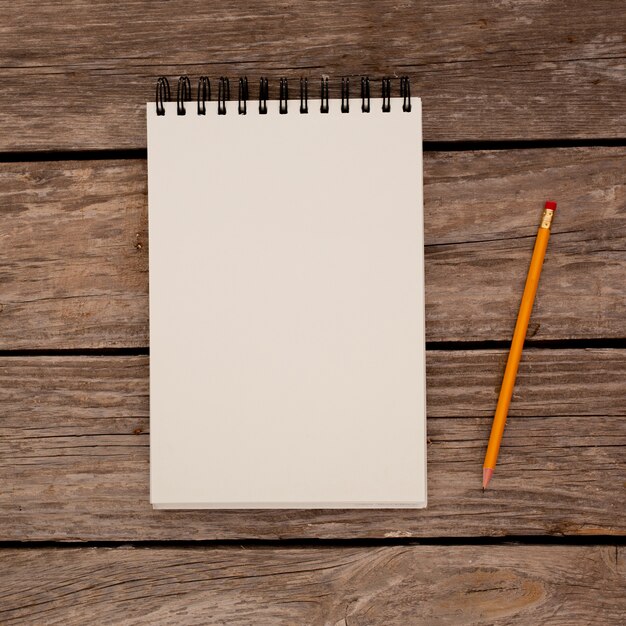 Notepad with pencil on wood board background