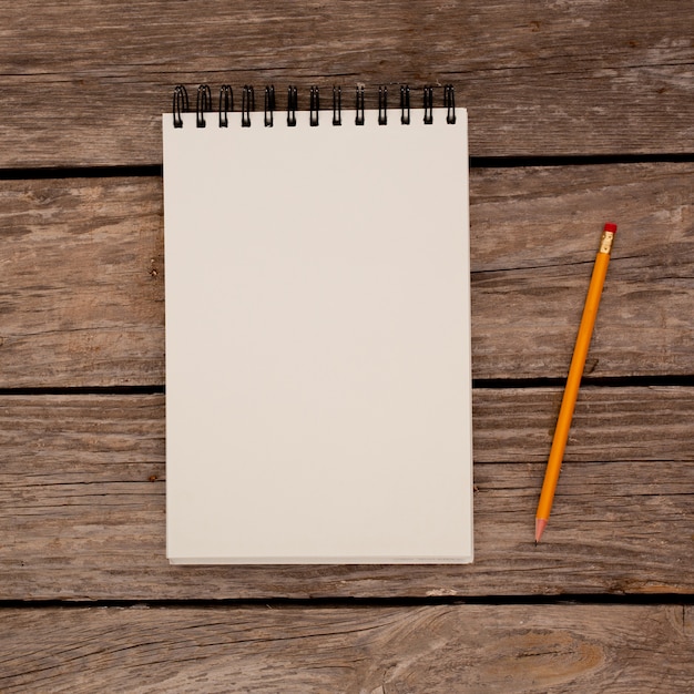 Notepad with pencil on wood board background