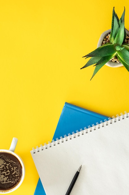 Free photo notepads and a cup of coffee on a yellow background flat lay