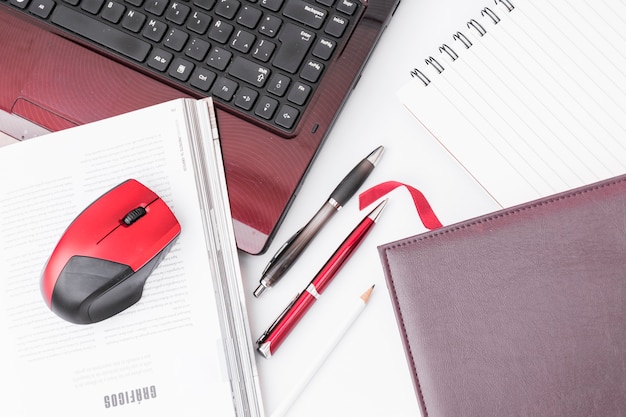 Notepads and pens near laptop and mouse