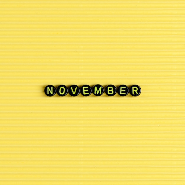 Foto gratuita novembre perline tipografia parola su giallo