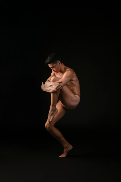 Nude dancer hugging knee