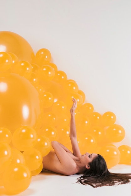 Бесплатное фото Обнаженная женщина между желтыми воздушными шарами