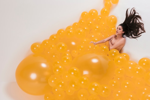 Foto gratuita donna nuda tra molti palloncini gialli