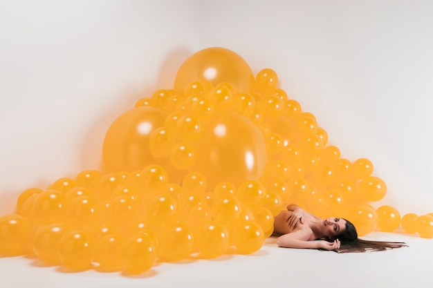 Foto gratuita donna nuda tra molti palloncini gialli