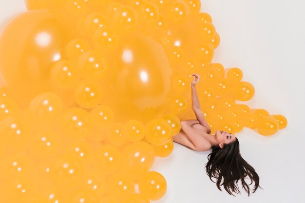 Nude woman between many yellow balloons