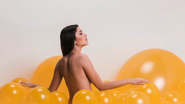 Free photo nude woman between many yellow balloons