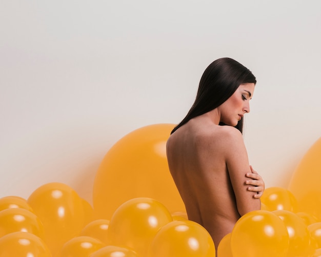 Nude woman between many yellow balloons