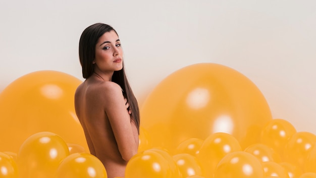 Обнаженная женщина между желтыми воздушными шарами