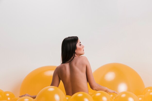多くの黄色い風船の間の裸の女性