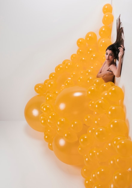 Nude woman between many yellow balloons