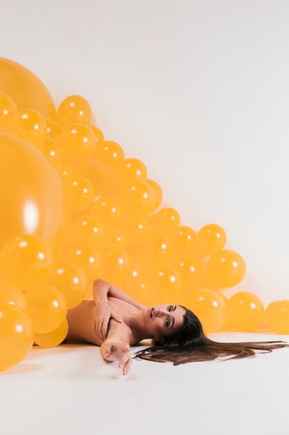 Nude woman between many yellow balloons