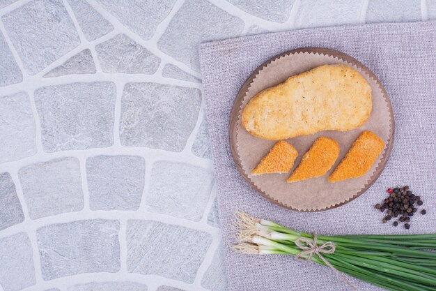 Nuggets on a wooden board with a bunch of green onions