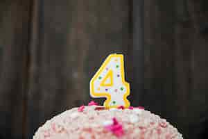 Foto gratuita candela di numero 4 in una torta di compleanno contro fondo di legno blu