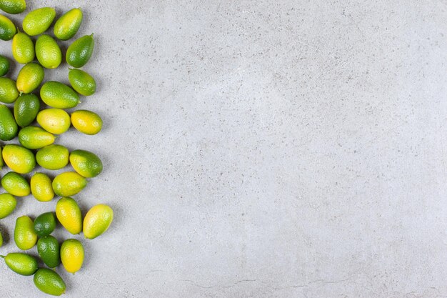 A number of kumquats scattered on marble background.