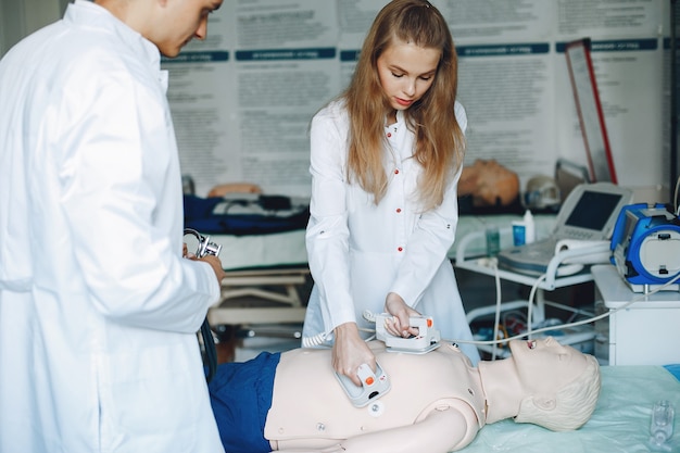 Nurse conducts resuscitation. Doctor helps woman to perform the operation. Students practice medicine.