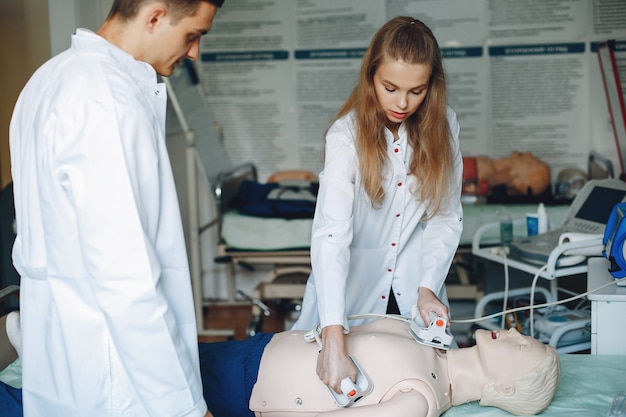 Nurse conducts resuscitation. Doctor helps woman to perform the operation. Students practice medicine.