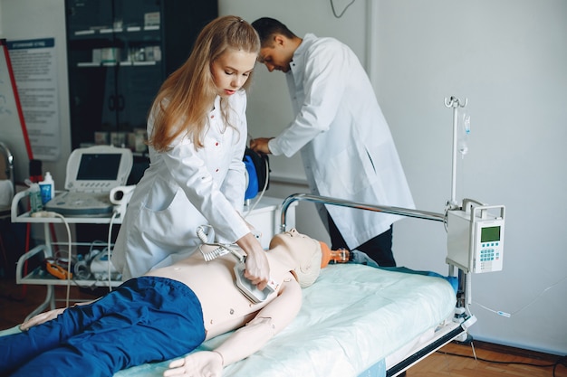 Nurse conducts resuscitation. Doctor helps woman to perform the operation. Students practice medicine.