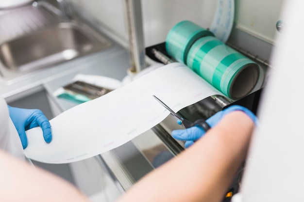 Nurse cutting plastic from pouch sealer packaging machinery