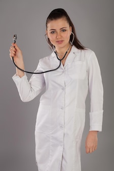 Nurse in gauze is against grey background with stethoscope