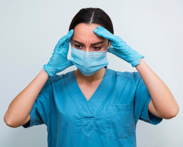 Free photo nurse having a headache while wearing a medical mask