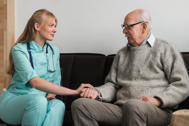 Nurse holding old man's hand in a nursing home