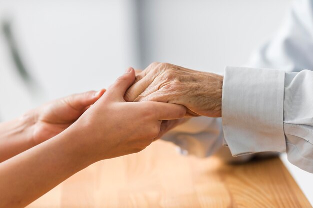 Nurse holding senior man's hands for comfort