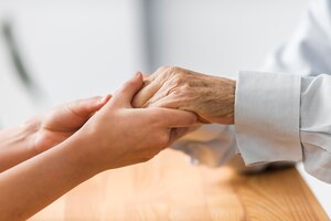 nurse holding senior man's hands for comfort