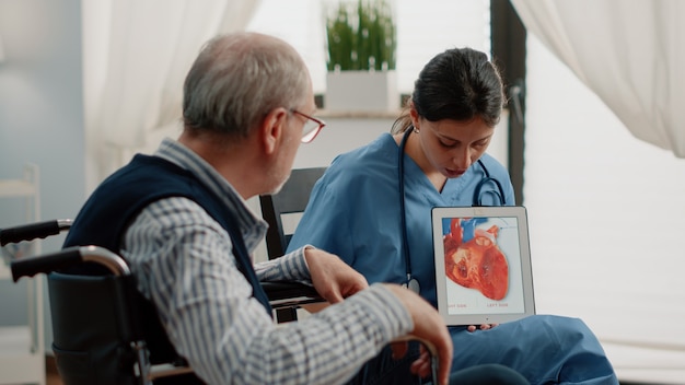 Foto gratuita infermiera che tiene compressa con la figura del cuore per la diagnosi di cardiologia