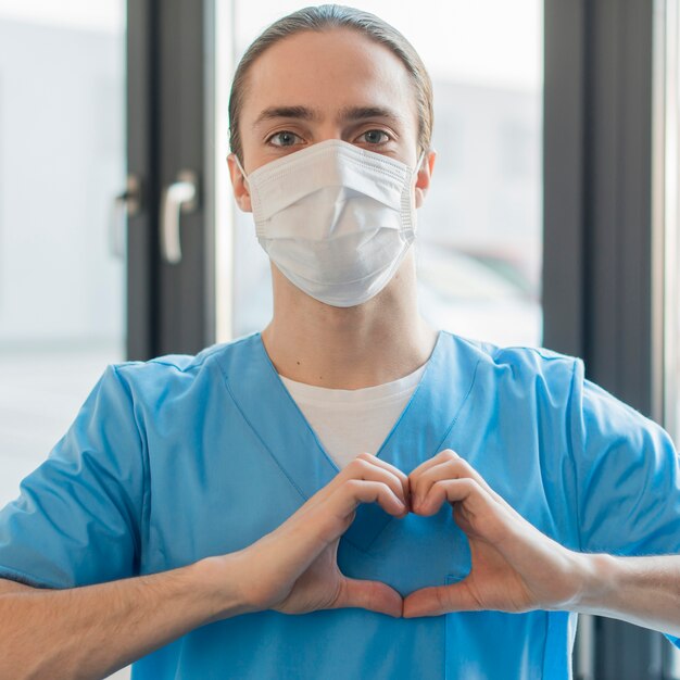 의료 마스크 심장 모양을 보여주는 간호사 남성