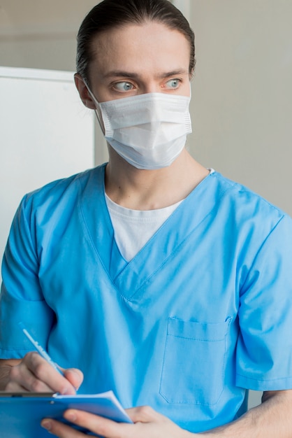Nurse male with medical mask with clipboard