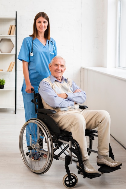 Nurse and old man posing while looking at the camera