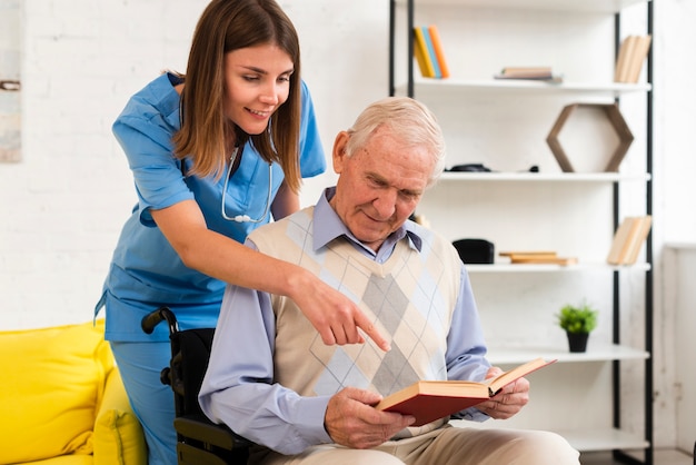 Nurse pointing to old man's book