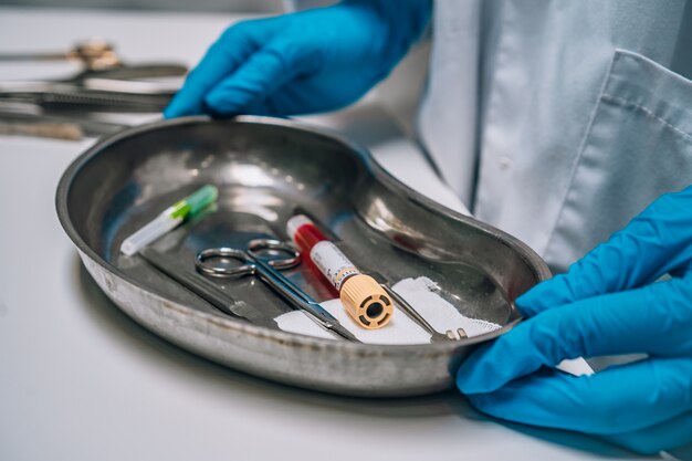 Nurse in rubber gloves holding a tray of surgical medical equipment