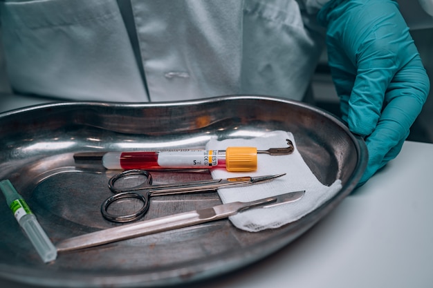 Nurse in rubber gloves holding a tray of surgical medical equipment