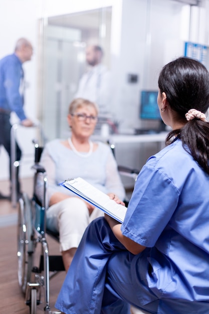 Free photo nurse talking with handicapped senior woman in wheelchair about her disablity