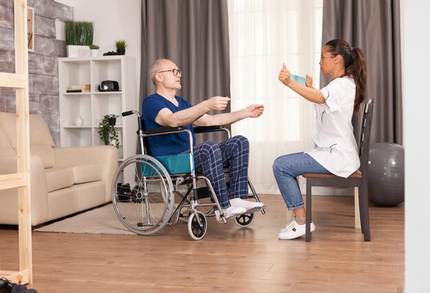 Nurse using resistance band and explain to the old man how to use it