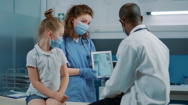 Nurse using tablet with human skeleton picture to give assistance to physician at checkup appointment. Medical worker holding osteopathy image to explain bones pain and diagnosis.