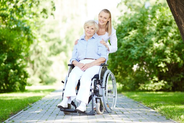 Nurse walking with senior patient in wheelchair