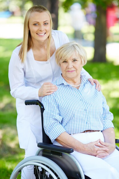 Медсестра с пожилой женщиной в инвалидной коляске